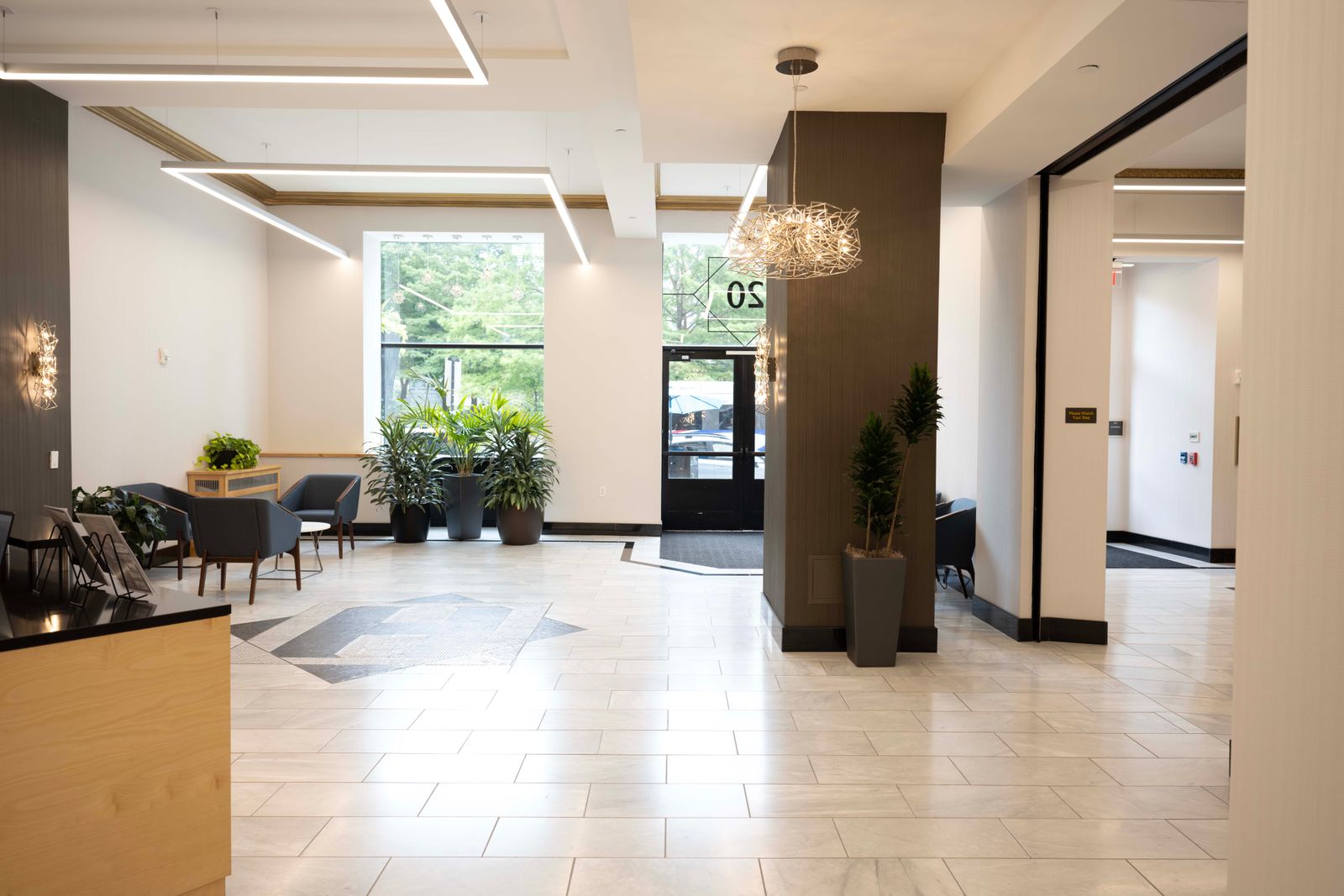 Renovated lobby with light stone tile, linear pendant lighting, and a seating area.